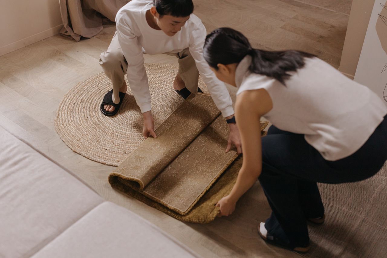 A couple rolls out a rug in a comfortable and stylish living room setting.